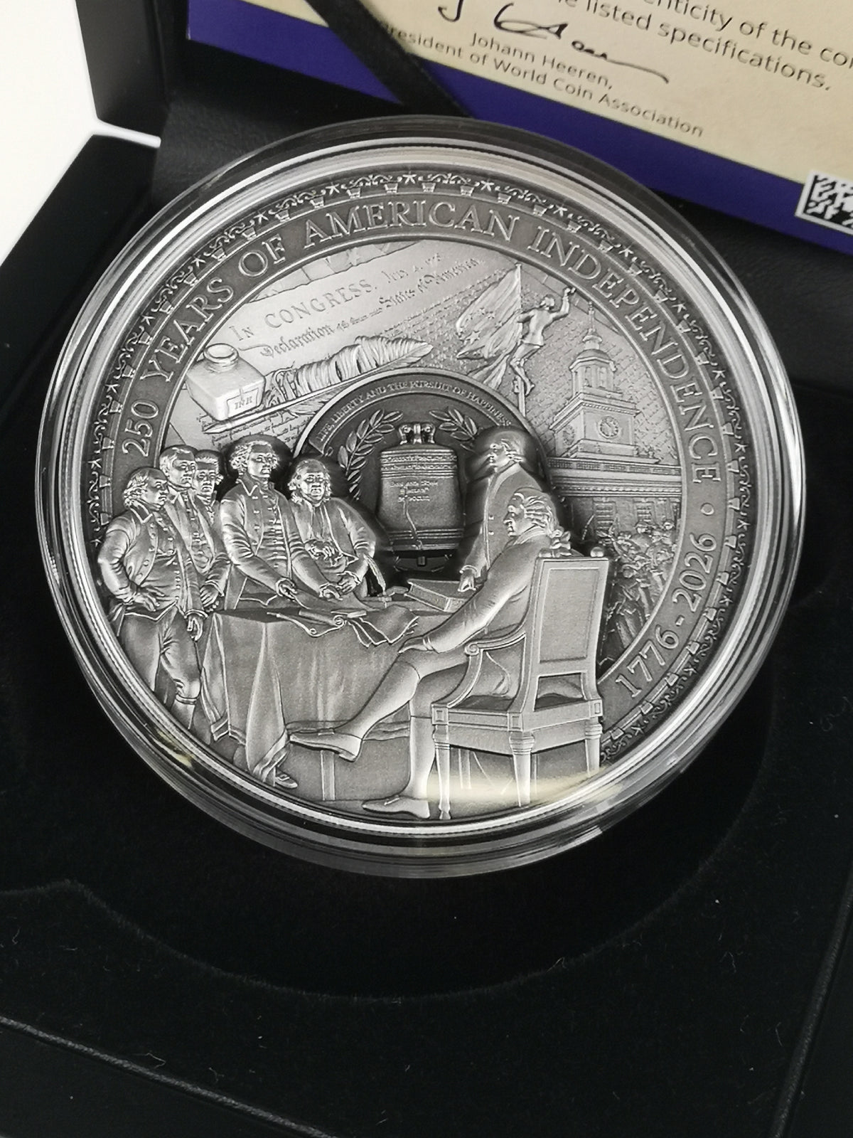 A round silver commemorative coin in a clear protective capsule, displayed inside a black presentation box. The coin features raised relief details of the Constitutional Convention.