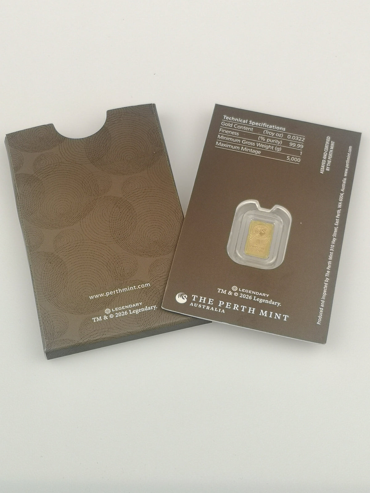 A Dune 1g gold bar from The Perth Mint in its original packaging, showing the textured brown envelope cover on the left and the technical specification card on the right.