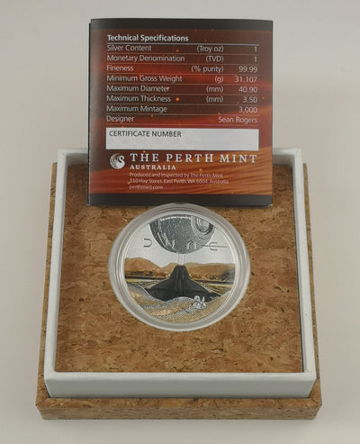 A Perth Mint Australia Dune silver coin in a clear protective capsule, displayed inside a cork-lined presentation box with a white insert. A technical specification card is placed above the coin.